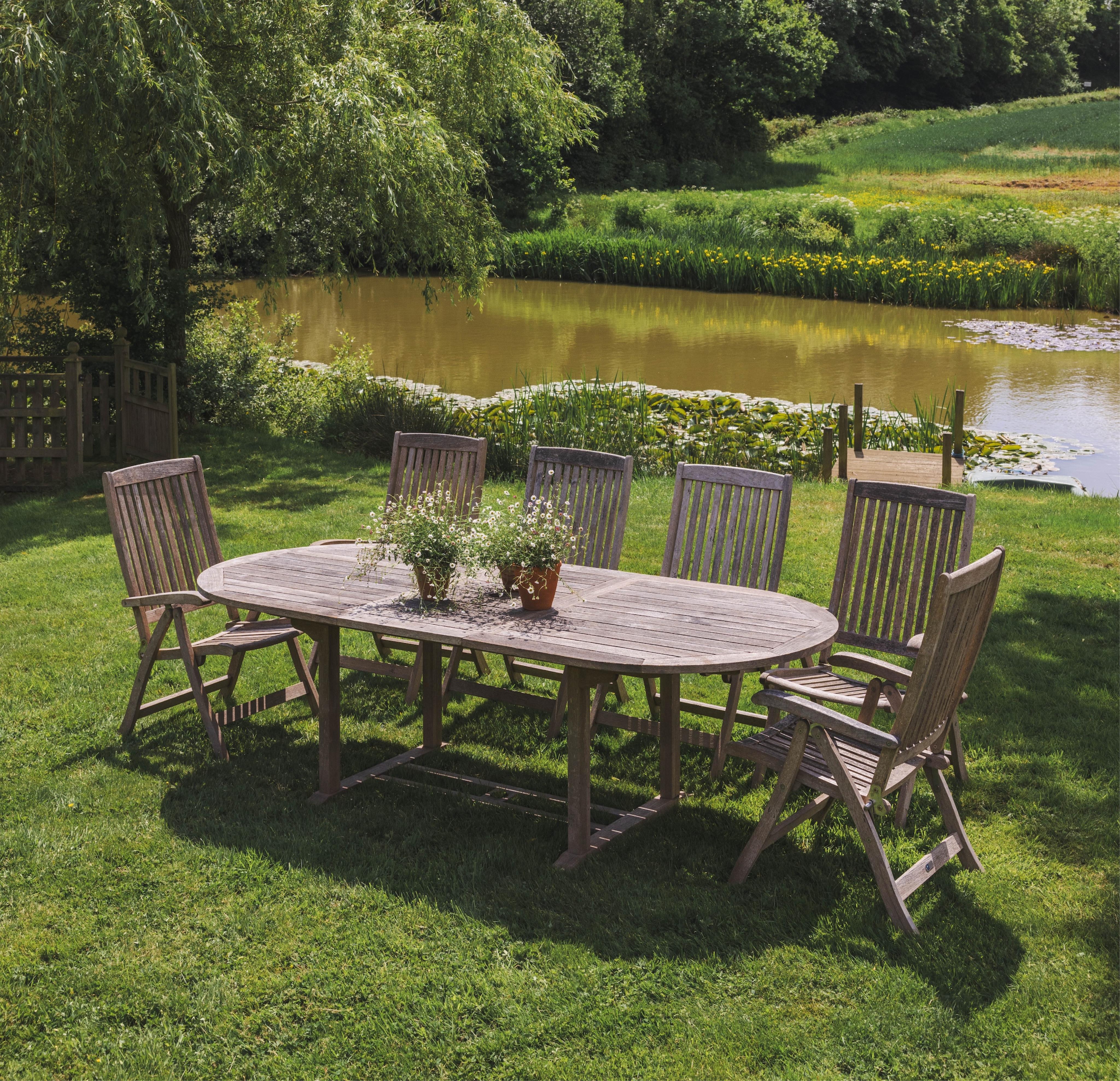 A weathered slatted teak Nova extending garden table, width 240cm extended, depth 100cm, height 71cm and six teak Alexander Rose folding chairs